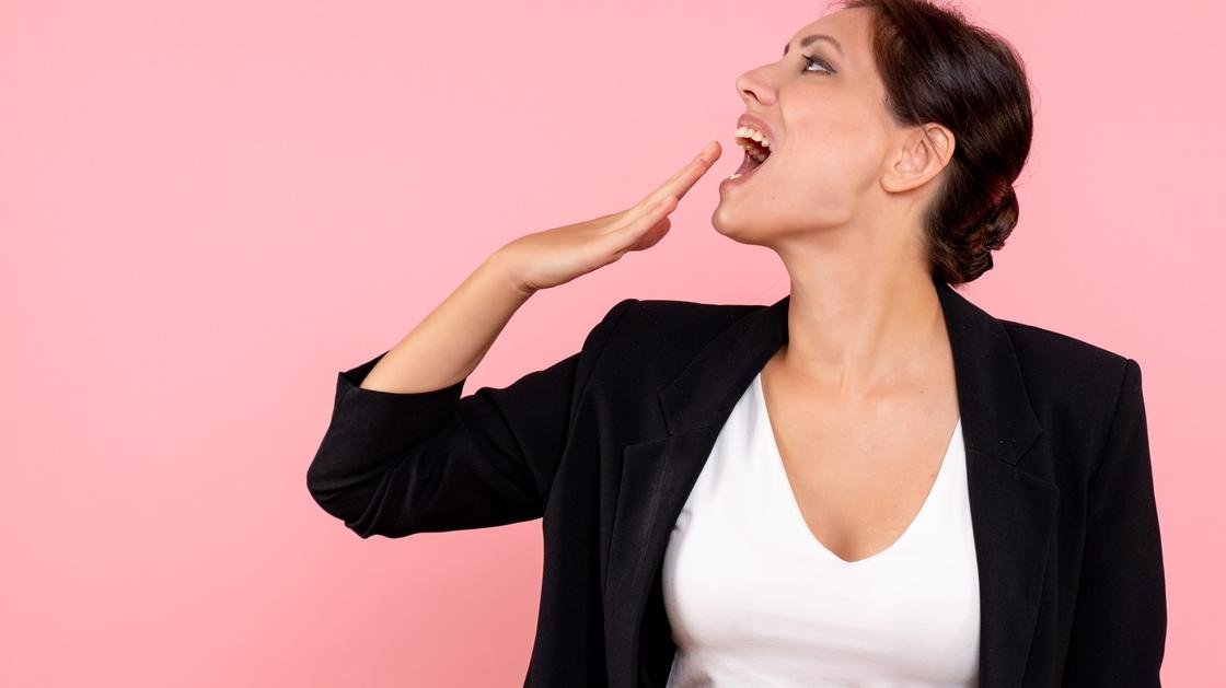 Дівчина в чорному піджаку співає і тримає руку біля рота